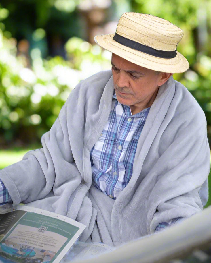 Man sitting outdoors reading a newspaper while wearing a  Snhug Sit sitting blanket

