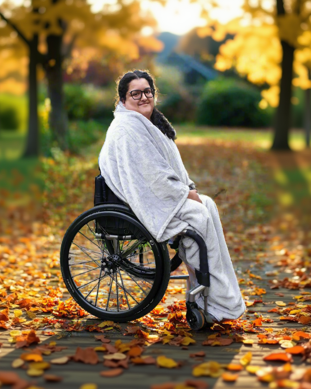 Wheelchair user seated wearing Snhug Sit blanket draped over the shoulders with arms free, showing upper body warmth without sleeves